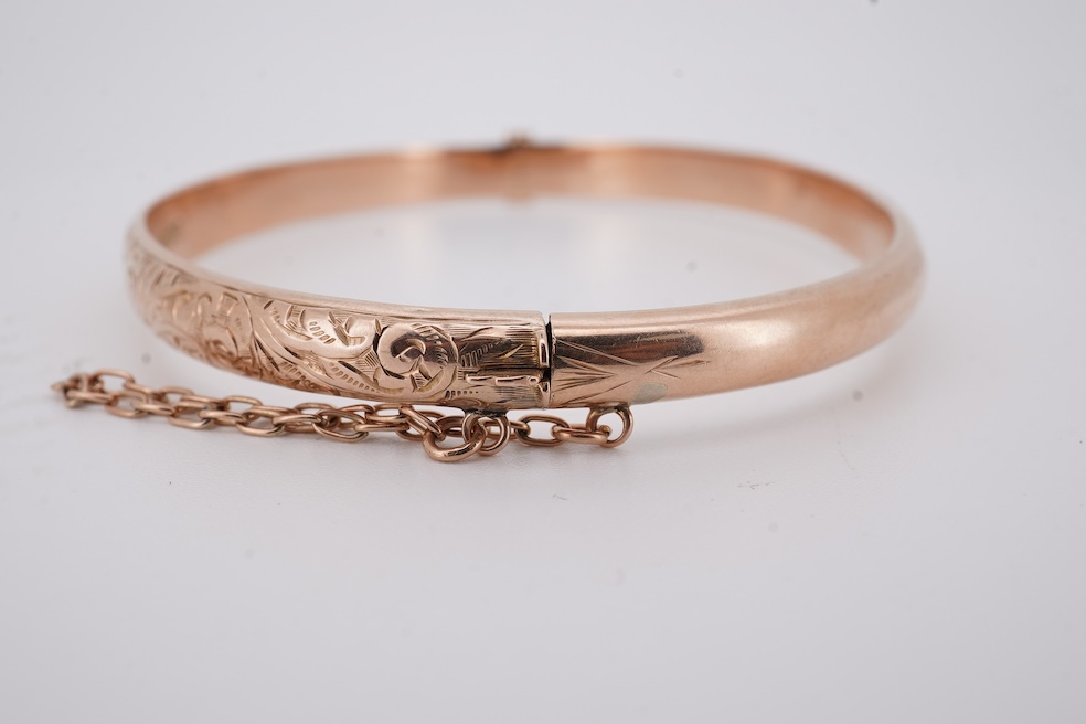 A George V part engraved 9ct gold hollow hinged bangle, Birmingham, 1911, interior diameter 57mm, 5.5 grams. Condition - poor